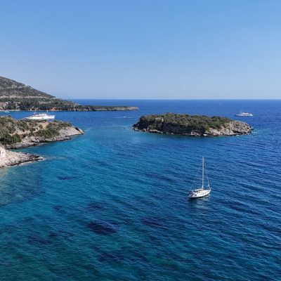 A stunning landscape of Kardamyli in Mani, featuring vibrant blue waters and traditional stone buildings against a mountainous backdrop.