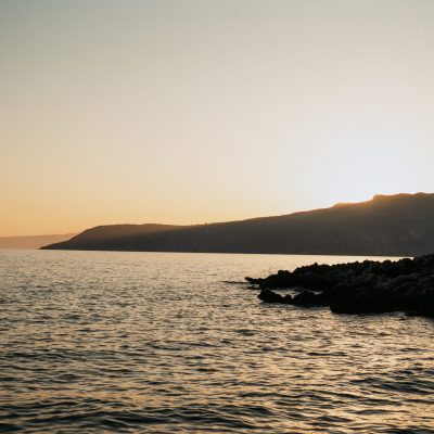 Sunset over the sea and mountains in Kardamyli, Mani, casting warm hues across the landscape.