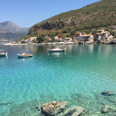 Scenic view of Kardamyli in Mani, featuring vibrant blue waters and rocky coastline under a clear sky.