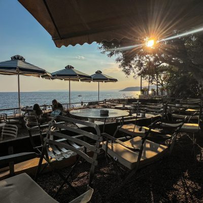 Sunset view from a beach bar in Kardamyli, Mani, showcasing vibrant colors over the tranquil sea.