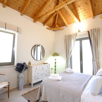 A cozy bedroom in Olive Grove villa, Kardamyli, featuring wooden beams and a neatly made bed.
