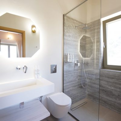 Interior view of a bathroom in Olive Grove villa, showcasing a sink, toilet, and shower in a modern setting.
